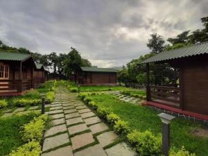 einen Steinweg in einem Garten mit Gebäuden im Hintergrund in der Unterkunft Cocorico Stay Ya! Cottages Alibag in Alibag
