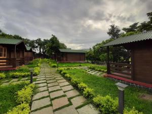 a stone path in a garden with buildings in the background at Cocorico Stay Ya! Cottages Alibag in Alibaug