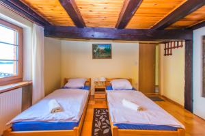 two beds in a room with a wooden ceiling at Karczma u Wallenroda in Ryn