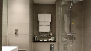 een badkamer met een douche en een glazen deur bij Holiday Inn Huntingdon Racecourse, an IHG Hotel in Huntingdon
