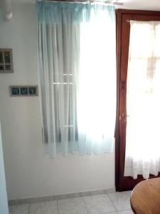 a white room with a window with white curtains at Violetta Studios & Apartments in Mil&iacute;na