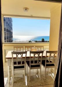 a dining room with a table and chairs and a large window at Superbe appartement face à la mer avec parking privatif in Canet-en-Roussillon