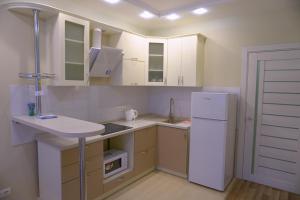 キーウにあるПосуточная аренда квартиры м. Левобережнаяの白いキャビネット、シンク、冷蔵庫付きのキッチンが備わります。