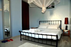 a bedroom with a bed with white sheets and a mirror at Victoria Lake View Guesthouse & Safaris in Entebbe