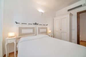 a white bedroom with a white bed and two lamps at 3BR Marina Apartment Porto Cervo in Porto Cervo