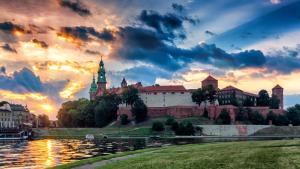 a castle on a hill next to a body of water at Golden Queen Apartments Jewish District in Kraków