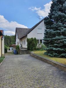 a white house with a tree next to a driveway at Ferienwohnung Deichblick 2 in Gerhardshofen