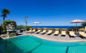 una piscina con sedie e ombrelloni e l'oceano di Parco Residence La Rosa a Ischia