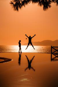 a man and woman jumping on the beach at sunset at Liberty Lykia in Oludeniz