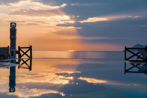 a pool with a lighthouse in the water at sunset at Liberty Lykia in Oludeniz