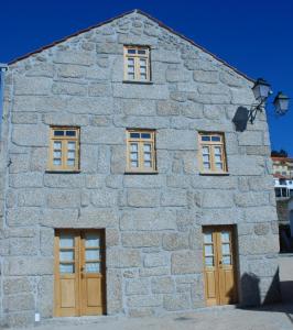 ein Steingebäude mit braunen Türen und Fenstern in der Unterkunft Casa da Moreia in Sabugueiro