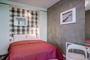 a bedroom with a red bed and a checkerboard wall at CHILLIapartamenty - Platany - POWDER in Kołobrzeg