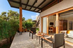 a patio with a bed and a table and chairs at Woods at Sasan in Sasan Gir