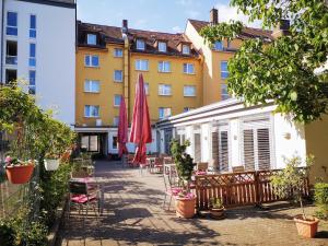 eine Terrasse mit Stühlen und Sonnenschirmen vor einem Gebäude in der Unterkunft Hotel Scholz in Koblenz