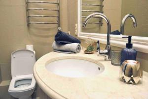 a bathroom with a sink and a toilet and a mirror at White&Light flat near Gulliver in Kyiv