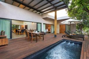 an outdoor deck with a dining table and a pool at Woods at Sasan in Sasan Gir
