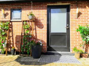 a brick house with a black door and potted plants at 5minute walk to LEGO house - private studio room with bathroom in Billund