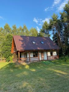 a house with a roof on a grass field at Domek nad Wkrą in Popielżyn Górny