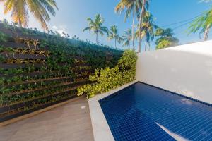 einen Hinterhof mit einem Pool und einem Zaun mit Pflanzen in der Unterkunft SOLAR DE PORTO RICO "Aptms" P GALINHAS in Porto De Galinhas