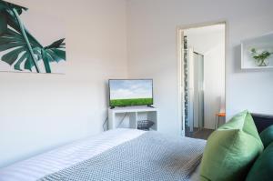 a white bedroom with a bed and a television at Cosy and Bright Studio Next to Westmead Hospital DUPLICATE in Sydney