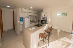 eine Küche mit einer Theke mit Hockern und einem Kühlschrank in der Unterkunft SOLAR DE PORTO RICO "Aptms" P GALINHAS in Porto De Galinhas