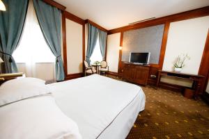 a hotel room with a white bed and a television at Hotel Select in Iaşi