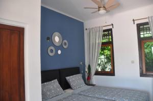 a blue bedroom with a bed and a ceiling fan at Guesthouse The 4 Fish in Manado