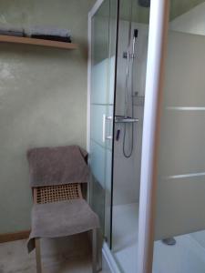 a chair in a bathroom with a glass shower at La Brevonniere in Beaulieu