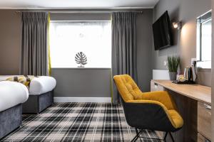 a hotel room with two beds and a chair at Roydon Marina Village Hotel in Roydon