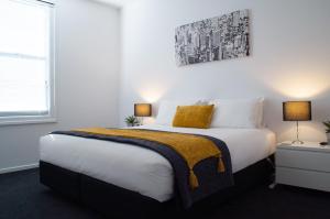 a bedroom with a large white bed with two lamps at Hobart Cityscape in Hobart