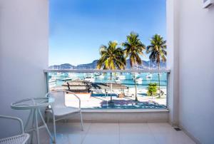 a balcony with a view of the ocean and palm trees at Hotel Ilhabela in Ilhabela