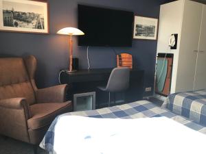 a hotel room with a bed and a chair and a television at West Side Hotel in Turku