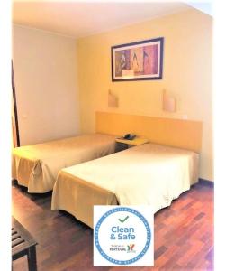 フンシャルにあるResidencial Chafariz /Queimadaのベッド2台(緑のサイン付)、セーフティボックスが備わるホテルルームです。