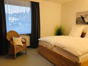 a bedroom with a bed and a chair and a window at Große Wohnung - Kamin - Balkon - Boxspringbett - Skiwiese in Braunlage
