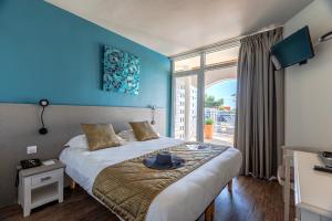 a bedroom with a bed with a hat on it at Hôtel Restaurant Le Grand Large - Face à la plage - Ile de Ré in Rivedoux-Plage