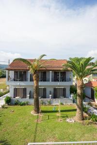 a house with two palm trees in front of it at MAKIS STUDIOS in Roda