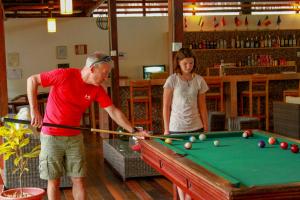 un hombre y una mujer jugando al billar en Heliconia Amazon River Lodge, en Francisco de Orellana