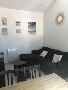 a living room with a black couch and a table at LE CHAI DE LA CHARENTAISE in Saint-Palais-sur-Mer