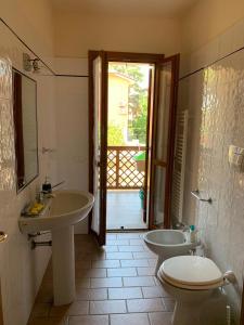 łazienka z 2 umywalkami, toaletą i oknem w obiekcie Casa Peonia w mieście Alberese