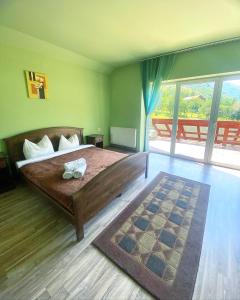 a bedroom with a large bed and a large window at Green House in Gura Râului