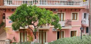 a pink building with a tree in front of it at Elpidas house in Parga