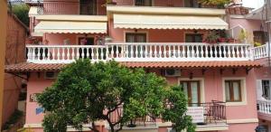 a pink building with a white balcony and a tree at Elpidas house in Parga +13 photos