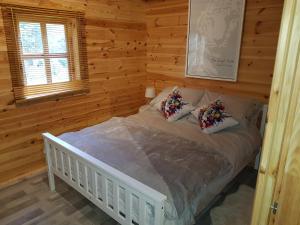 um quarto com uma cama branca num chalé de madeira em Cabin at Aithernie em Leven-Fife