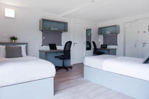 two beds in a room with a desk at Swuite Dublin in Dublin