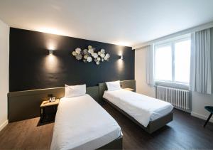 a hotel room with two beds and a black wall at Hotel Cortina in Wevelgem