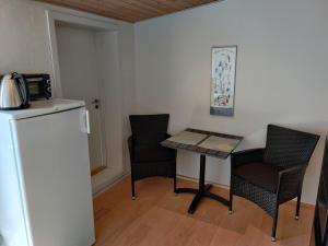 una pequeña cocina con mesa, sillas y nevera. en Hedegaard Anneks Skærbæk en Herning