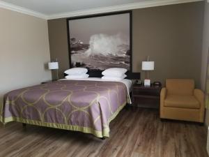 
a bedroom with a bed, chair, and a painting on the wall at Super 8 by Wyndham Los Angeles-Culver City Area in Los Angeles
