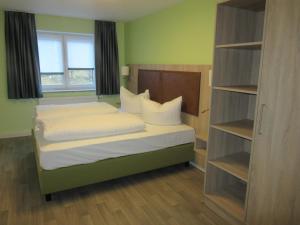 TIPTOP Hotel-Gasthaus Steiger في Gräfenthal: غرفة نوم بسرير وملاءات بيضاء ونافذة