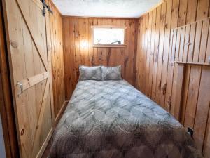 um pequeno quarto com uma cama num chalé de madeira em Tracadie Cottages em York