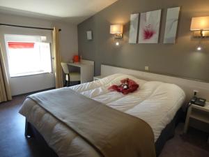 a bedroom with a bed with a red stuffed animal on it at Hotel du Centre in Pierrelatte